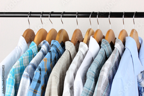 Photo: Shirts with ties on wooden hangers on light background Shirts with ties on wooden hangers on light background