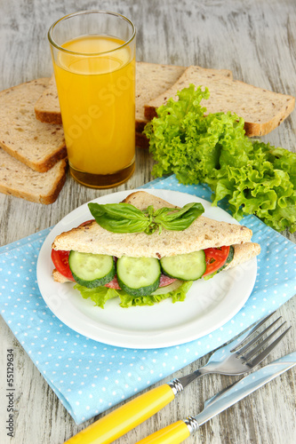 Photo: Composition with fruit juice and tasty sandwich with salami Composition with fruit juice and tasty sandwich with salami