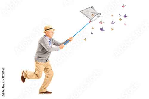 Photo: Mature man running and catching butterlies with net Mature man running and catching butterlies with net