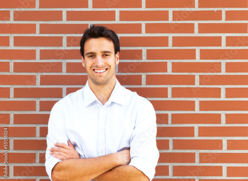 Photo: Handsome latin guy in front of a brick wall Handsome latin guy in front of a brick wall