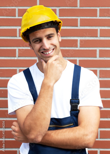 Photo: Friendly smiling worker in front of a brick wall Friendly smiling worker in front of a brick wall