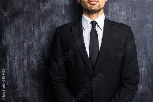 Photo: Businessman in front of blank blackboard Businessman in front of blank blackboard