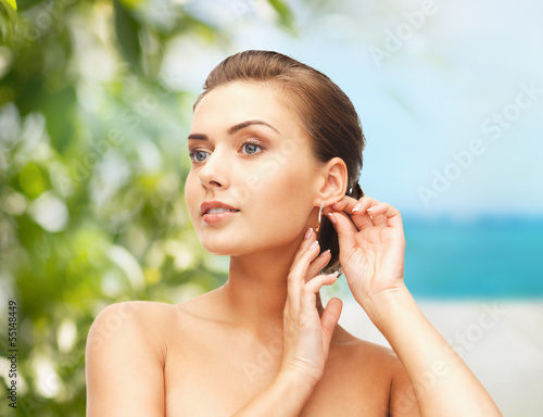 Photo: beautiful woman trying on gold earrings beautiful woman trying on gold earrings
