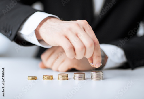 Photo: man putting stack of coins into one row man putting stack of coins into one row