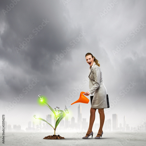 Photo: Business woman watering monet tree Business woman watering monet tree