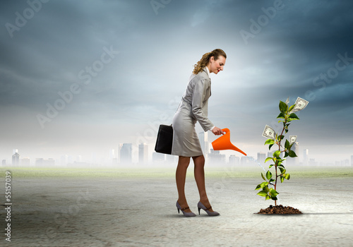 Photo: Business woman watering monet tree Business woman watering monet tree