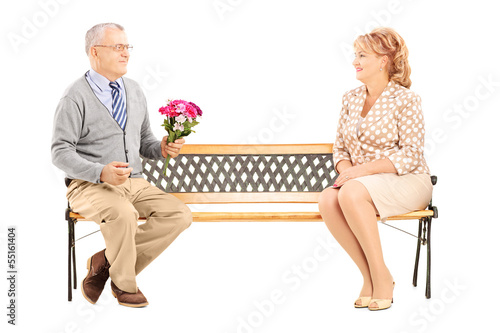 Photo: Mature gentleman giving a flower bouquet to a woman and sitting Mature gentleman giving a flower bouquet to a woman and sitting