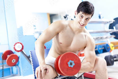Photo: Smiling handsome man lifting heavy free weights at the gym Smiling handsome man lifting heavy free weights at the gym