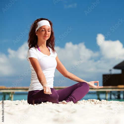Photo: Pretty woman doing yoga exercises on the tropical beach Pretty woman doing yoga exercises on the tropical beach