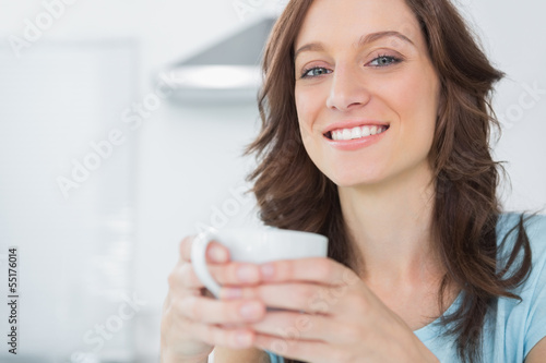 Photo: Cheerful brunette holding cup of coffee Cheerful brunette holding cup of coffee
