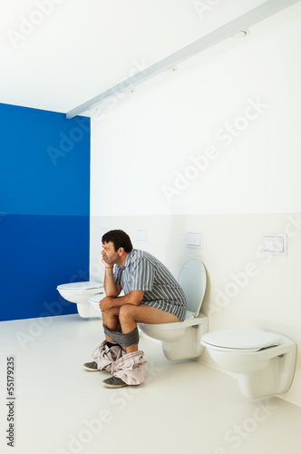 Photo: Man sitting on the toilet, public bathroom Man sitting on the toilet, public bathroom