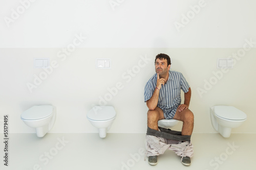 Photo: Man sitting on the toilet, public bathroom Man sitting on the toilet, public bathroom