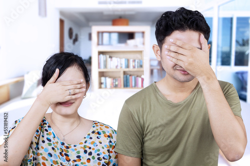 Photo: Asian couple cover faces at home Asian couple cover faces at home