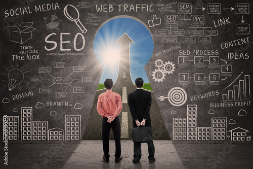 Photo: Business partners and SEO doodle on blackboard Business partners and SEO doodle on blackboard