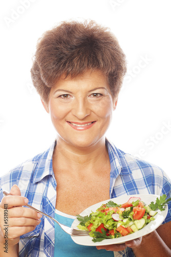 Photo: Mature smiling woman eating salad Mature smiling woman eating salad