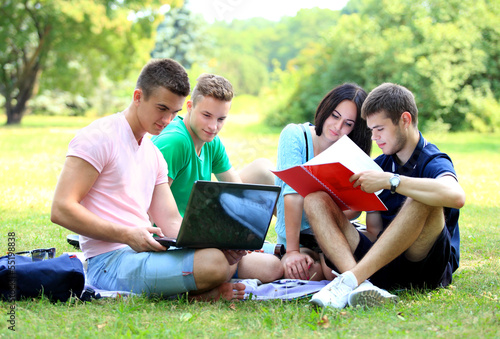 Photo: four smiling student studying in green park four smiling student studying in green park
