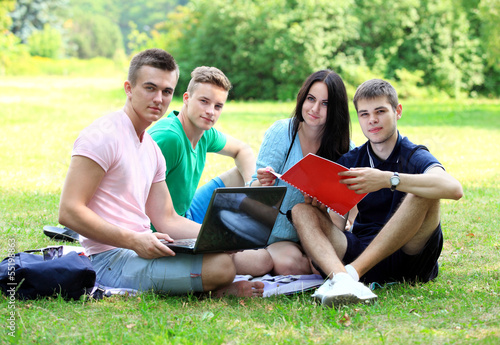 Photo: four smiling student studying in green park four smiling student studying in green park