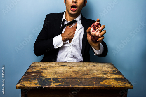 Photo: Man with chest pains holding a heart in his hand Man with chest pains holding a heart in his hand