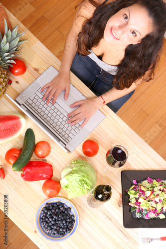 Photo: Woman using a Laptop while cooking Woman using a Laptop while cooking