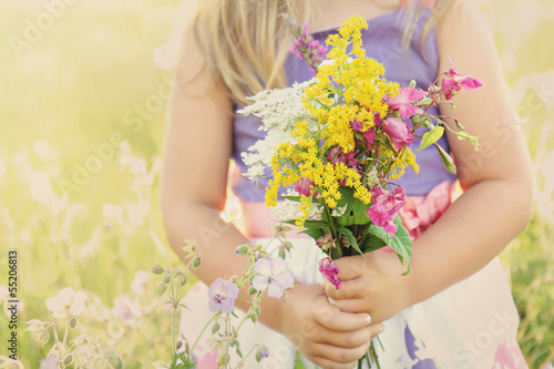 Photo: Little girl with flowers on grassy field Little girl with flowers on grassy field