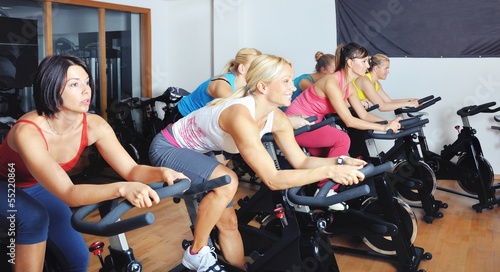 Photo: Beautiful women doing exercise in a spinning class at gym Beautiful women doing exercise in a spinning class at gym