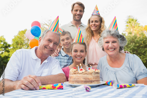 Photo: Cheeful family smiling at camera at birthday party Cheeful family smiling at camera at birthday party