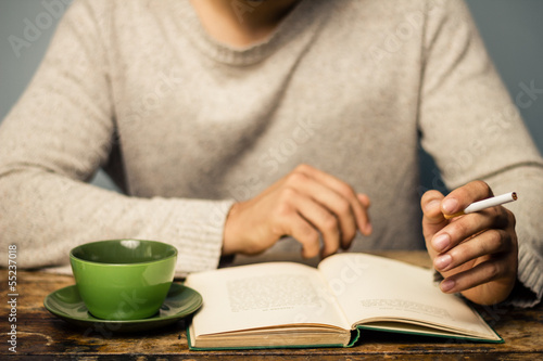 Photo: Man is reading and smoking in cafe Man is reading and smoking in cafe
