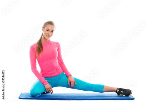 Photo: Beautiful fitness girl sitting on floor mat Beautiful fitness girl sitting on floor mat
