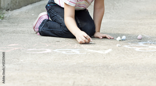 Photo: Back to school concept girl drawing with chalk in the schoolyard Back to school concept girl drawing with chalk in the schoolyard