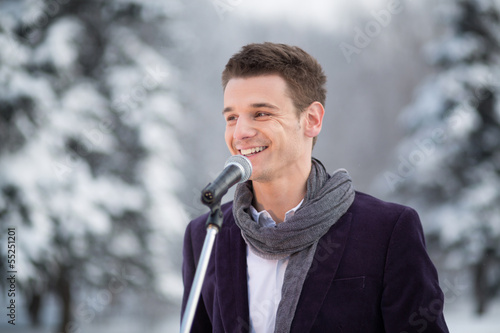 Photo: singer in suit and scarf stands outdoors in winter singer in suit and scarf stands outdoors in winter