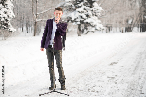 Photo: The singer in a suit and a scarf stands and sing outdoors The singer in a suit and a scarf stands and sing outdoors