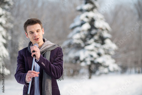 Photo: The singer in suit sing holding microphone in winter The singer in suit sing holding microphone in winter