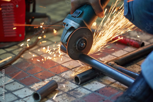 Photo: Male hand cuts off pieces of water pipe with angle grinder Male hand cuts off pieces of water pipe with angle grinder