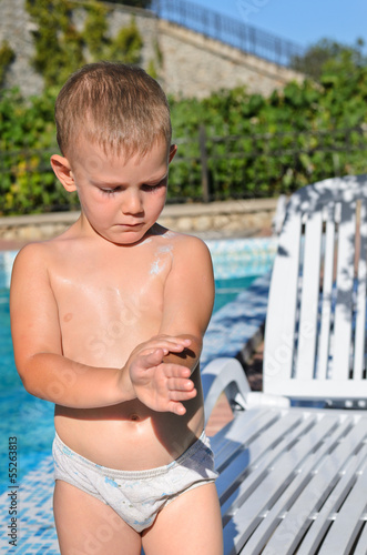 Photo: Careful little boy applying sunscreen Careful little boy applying sunscreen