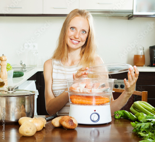 Photo: happy woman cooking with electric steame happy woman cooking with electric steame