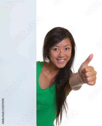 Photo: Asian woman showing thumb behind a signboard Asian woman showing thumb behind a signboard