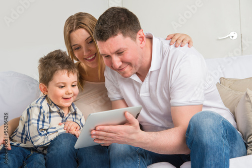 Photo: Happy family at home using electronic tablet Happy family at home using electronic tablet