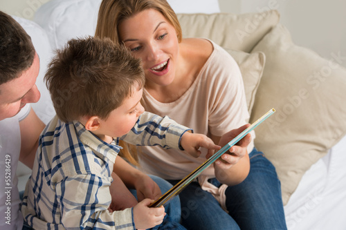 Photo: Parents Sitting With Child Reading Story Indoors Parents Sitting With Child Reading Story Indoors