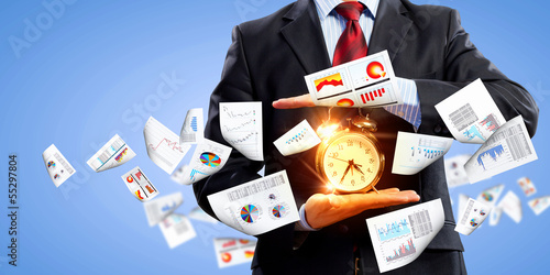Photo: Business man holding alarmclock Business man holding alarmclock