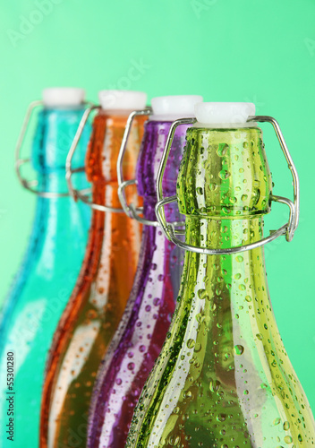 Photo: Colorful bottles on green background Colorful bottles on green background