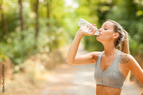 Photo: Young woman is drinking water after running session Young woman is drinking water after running session