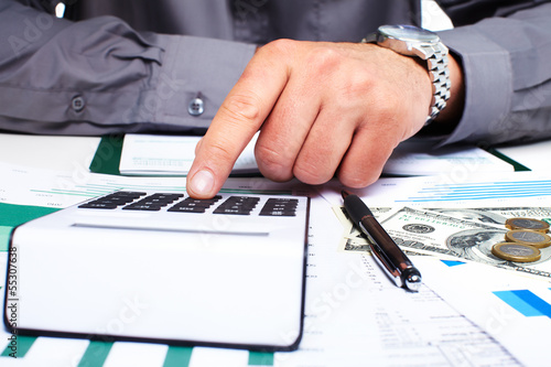Photo: Hand with calculator and money. Hand with calculator and money.
