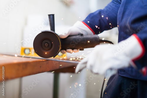 Photo: Worker cutting a metal plate Worker cutting a metal plate