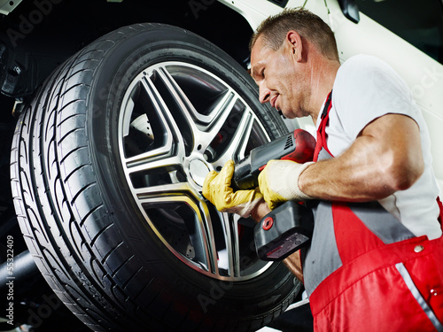 Photo: Motor mechanic is changing a tyre with new alu rim Motor mechanic is changing a tyre with new alu rim