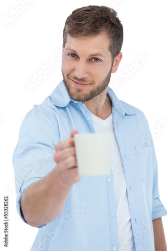 Photo: Smiling young model offering a mug Smiling young model offering a mug