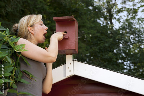 Photo: Frau im Garten kontrolliert Vogelhaus Frau im Garten kontrolliert Vogelhaus