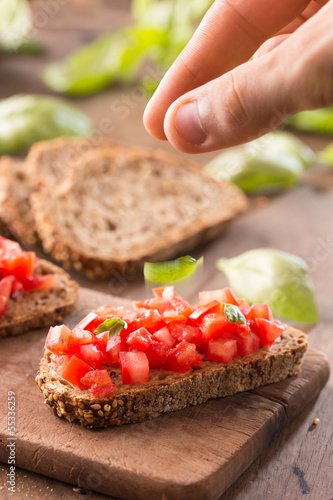 Photo: Hand preparing Italian bruschetta Hand preparing Italian bruschetta