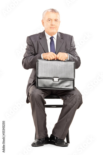 Photo: Mature businessman in suit holding a briefcase and waiting Mature businessman in suit holding a briefcase and waiting