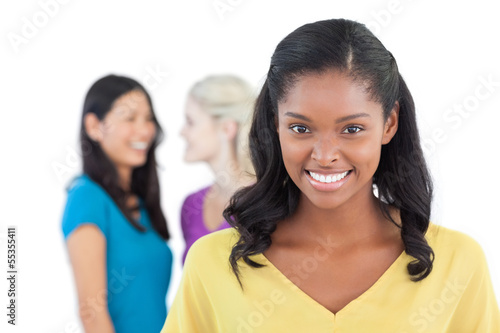 Photo: Smiling dark woman looking at camera with two women behind her Smiling dark woman looking at camera with two women behind her