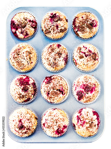 Photo: Fresh muffins in paper cupcake holder in baking pan isolated on Fresh muffins in paper cupcake holder in baking pan isolated on